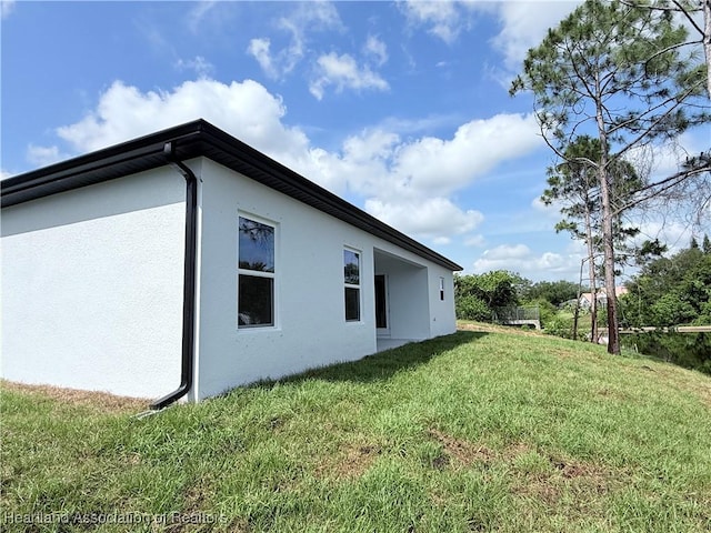 view of side of property with stucco siding and a yard