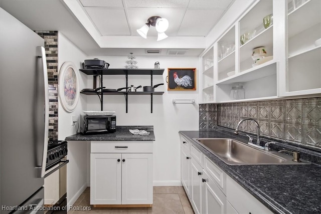 kitchen featuring backsplash, sink, black appliances, white cabinets, and light tile patterned flooring