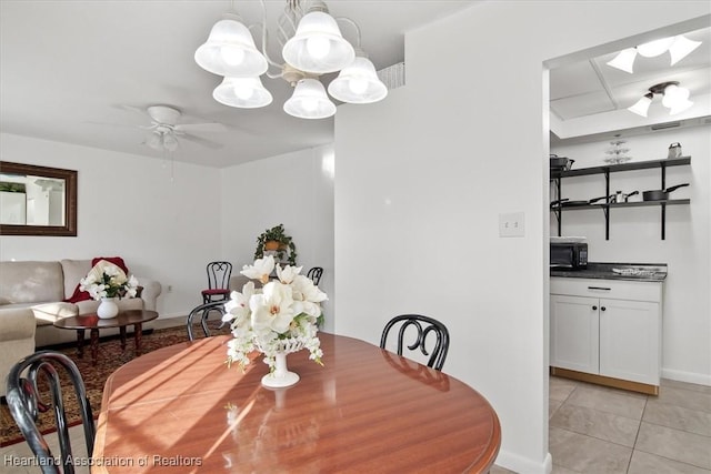 tiled dining space with ceiling fan with notable chandelier