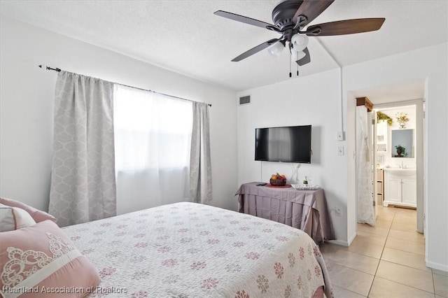 bedroom with ceiling fan, light tile patterned floors, and ensuite bathroom