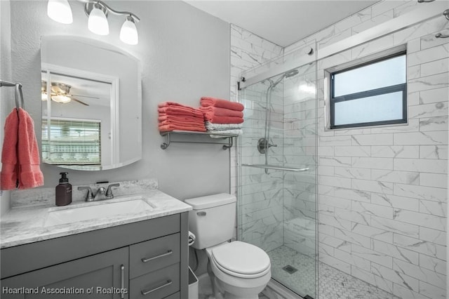 bathroom with ceiling fan, vanity, toilet, and a shower with shower door