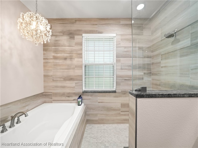 bathroom with an inviting chandelier, separate shower and tub, and tile walls