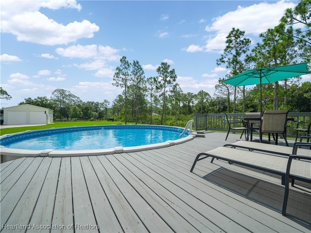 view of pool featuring a wooden deck, a garage, and an outdoor structure