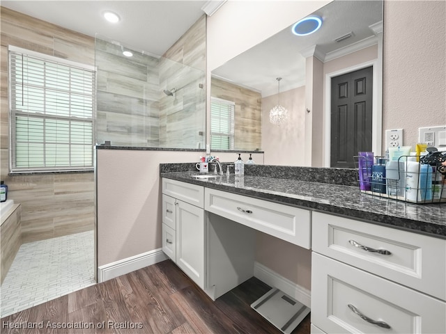 bathroom featuring ornamental molding, tiled shower, vanity, and an inviting chandelier