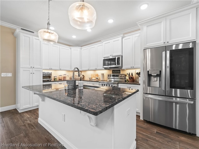 kitchen with appliances with stainless steel finishes, white cabinets, a kitchen breakfast bar, ornamental molding, and a kitchen island with sink