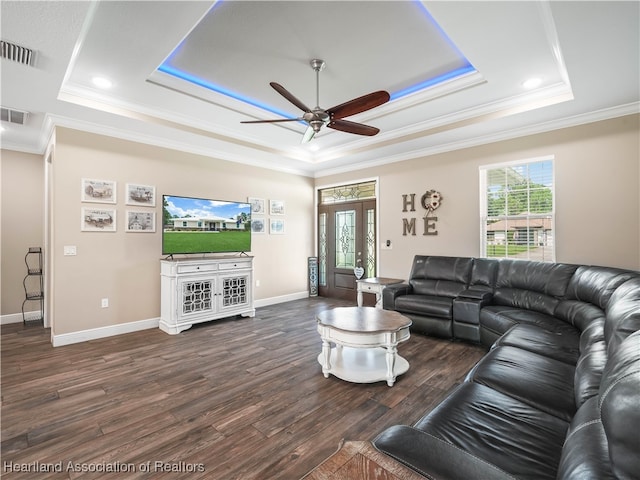 living room with dark wood-type flooring, ornamental molding, and a raised ceiling