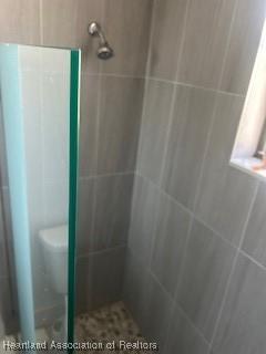 bathroom with toilet and tiled shower