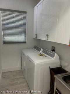 clothes washing area with a sink, separate washer and dryer, cabinet space, and baseboards