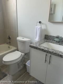 bathroom featuring toilet, shower / bathtub combination, and vanity