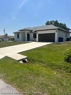 prairie-style home featuring concrete driveway, a front yard, and an attached garage