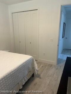 bedroom with baseboards, wood finished floors, and a closet