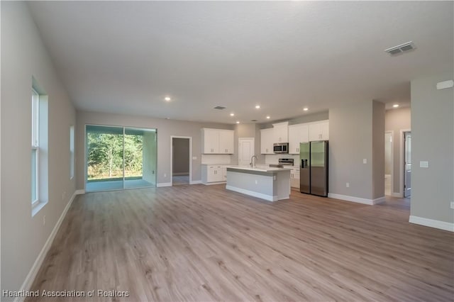 kitchen with sink, light hardwood / wood-style flooring, stainless steel appliances, white cabinets, and a center island with sink