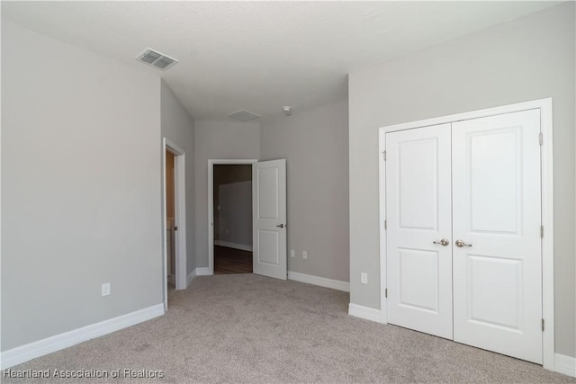 unfurnished bedroom featuring light colored carpet and a closet