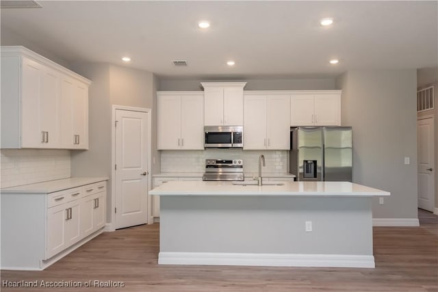 kitchen featuring stainless steel appliances, an island with sink, sink, and white cabinets