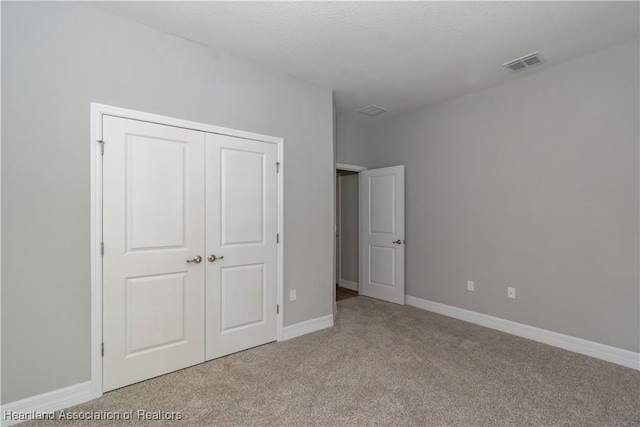 unfurnished bedroom with light colored carpet and a closet