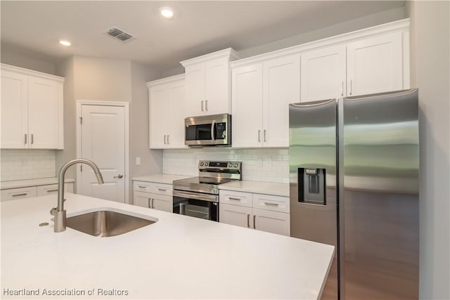 kitchen with white cabinetry, stainless steel appliances, sink, and backsplash