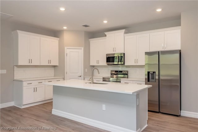 kitchen featuring white cabinetry, appliances with stainless steel finishes, and an island with sink