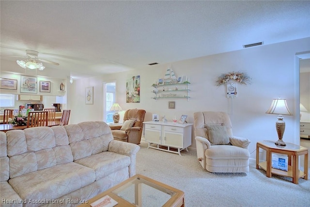 carpeted living room with a textured ceiling and ceiling fan