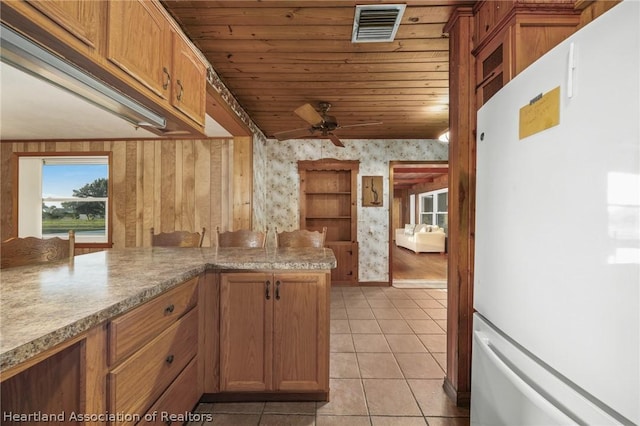 kitchen featuring kitchen peninsula, ceiling fan, light tile patterned floors, wooden ceiling, and white fridge