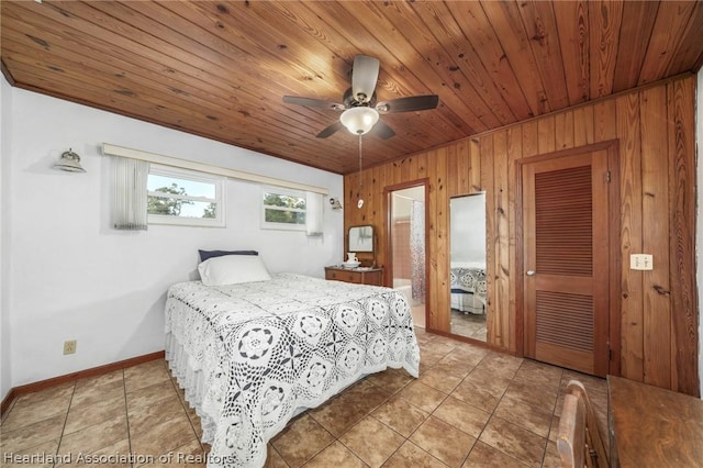 tiled bedroom featuring ceiling fan, wood walls, and ensuite bath