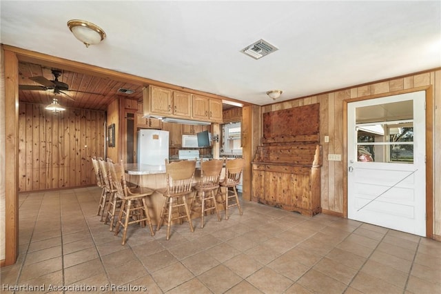 unfurnished dining area with ceiling fan and wood walls