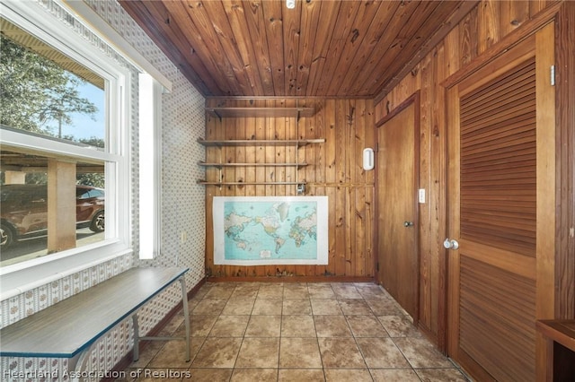 interior space with light tile patterned flooring, wooden walls, and wood ceiling