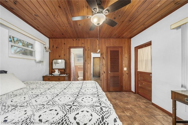 tiled bedroom with multiple windows, connected bathroom, ceiling fan, and wood walls