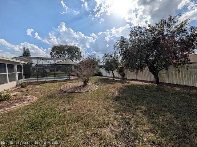 view of yard featuring a lanai, fence, and a fenced in pool