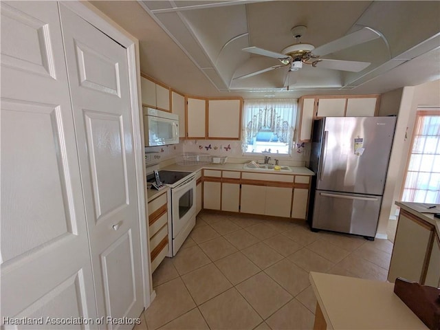 kitchen featuring cream cabinetry, light tile patterned floors, white appliances, and sink