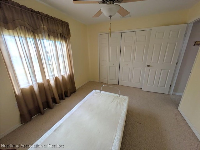 bedroom with ceiling fan, light colored carpet, and a closet