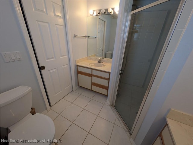 bathroom with a shower with door, vanity, tile patterned floors, and toilet