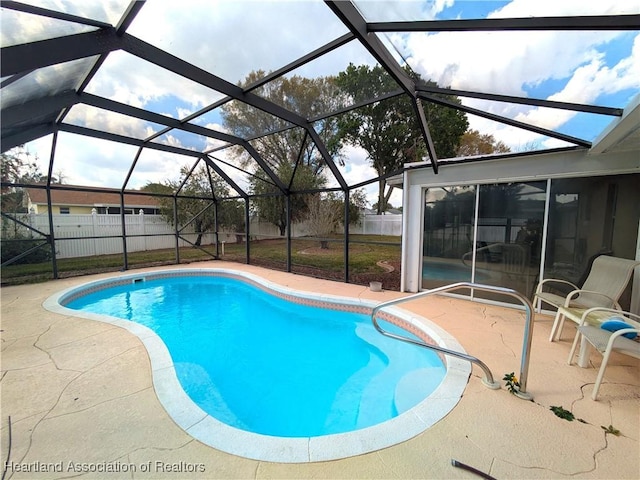 outdoor pool featuring glass enclosure, a patio, and a fenced backyard