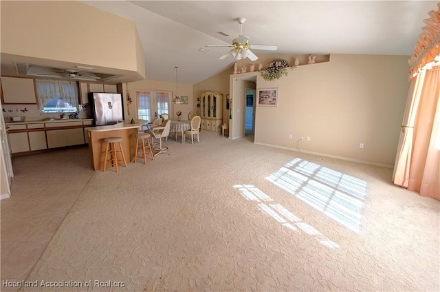 kitchen with a kitchen island, freestanding refrigerator, ceiling fan, vaulted ceiling, and a kitchen bar