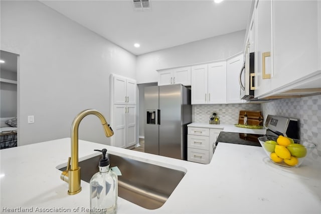 kitchen featuring appliances with stainless steel finishes, backsplash, white cabinetry, and sink