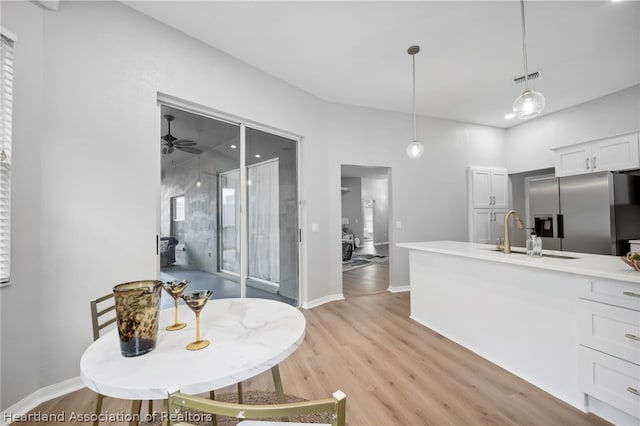 kitchen with ceiling fan, sink, stainless steel refrigerator with ice dispenser, pendant lighting, and white cabinets