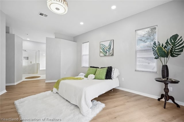 bedroom featuring connected bathroom, light hardwood / wood-style flooring, and multiple windows