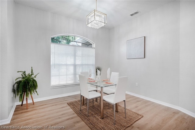 dining area with light hardwood / wood-style flooring, plenty of natural light, and a notable chandelier