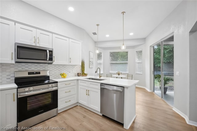 kitchen with white cabinetry, sink, hanging light fixtures, and appliances with stainless steel finishes