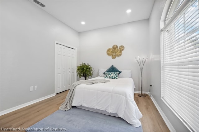 bedroom with light hardwood / wood-style floors and a closet