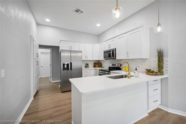 kitchen featuring pendant lighting, sink, kitchen peninsula, white cabinetry, and stainless steel appliances