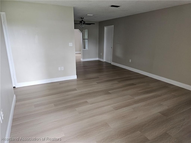 spare room featuring ceiling fan, light hardwood / wood-style floors, and a textured ceiling