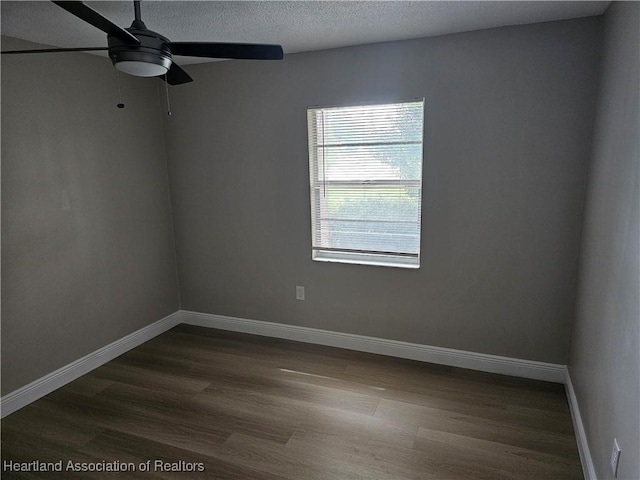 spare room with a textured ceiling, ceiling fan, and dark wood-type flooring