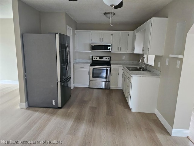 kitchen with sink, white cabinetry, stainless steel appliances, and light wood-type flooring