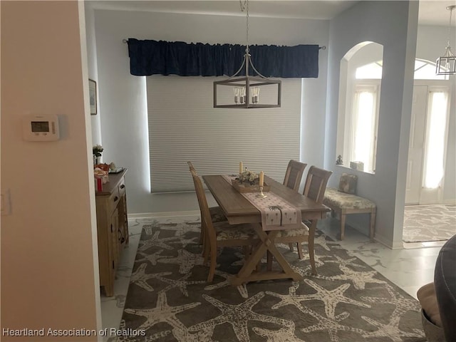 dining area with marble finish floor, baseboards, arched walkways, and a notable chandelier