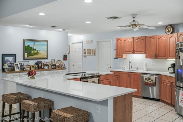 kitchen with light countertops, visible vents, appliances with stainless steel finishes, a sink, and a kitchen bar