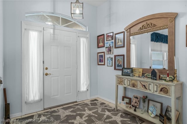 tiled entrance foyer with a healthy amount of sunlight and baseboards