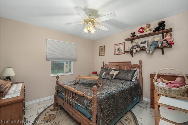 bedroom featuring a ceiling fan, marble finish floor, and baseboards