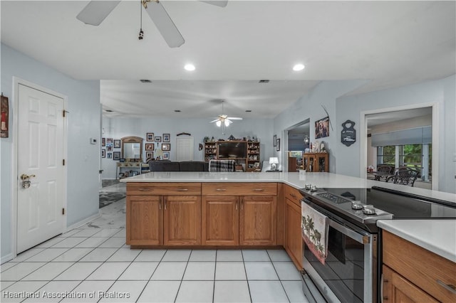 kitchen with a ceiling fan, brown cabinets, open floor plan, light countertops, and stainless steel range with electric stovetop