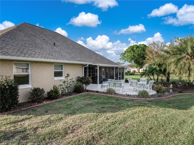 back of property with a sunroom, a shingled roof, a yard, and stucco siding