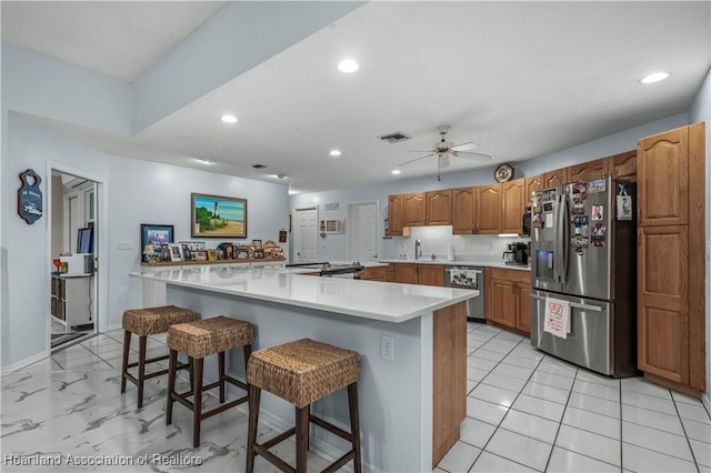 kitchen with a breakfast bar, recessed lighting, light countertops, appliances with stainless steel finishes, and ceiling fan